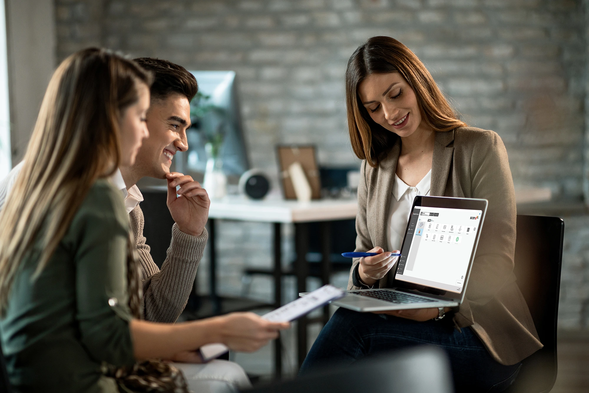 smiling-real-estate-agent-using-computer-while-having-meeting-with-young-couple-making-investment-plans